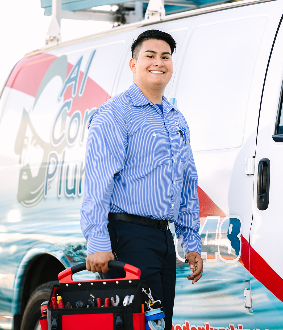 Al Coronado plumber holding a toolbox in front of a service van.