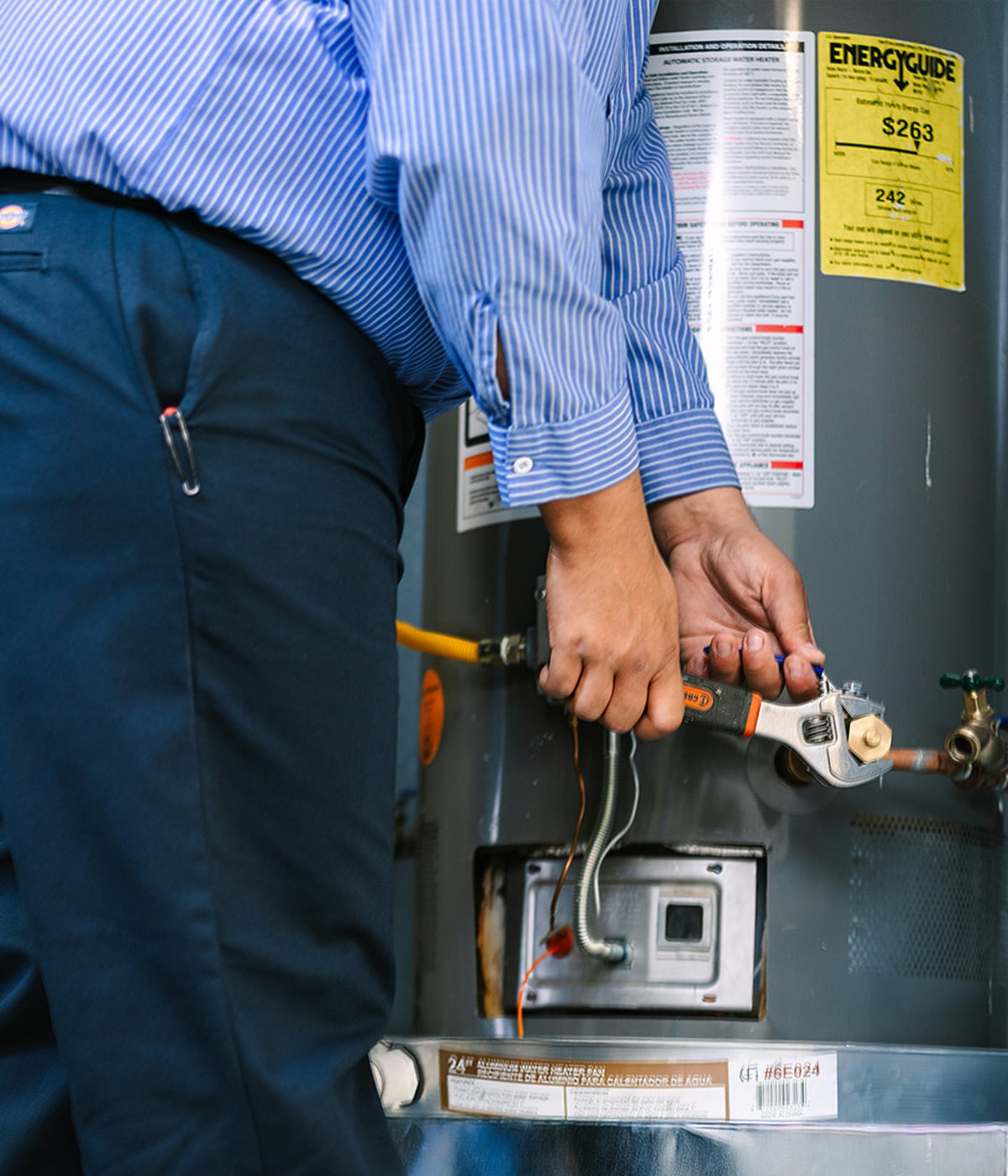 Al Coronado plumber using a wrench to repair a water heater.