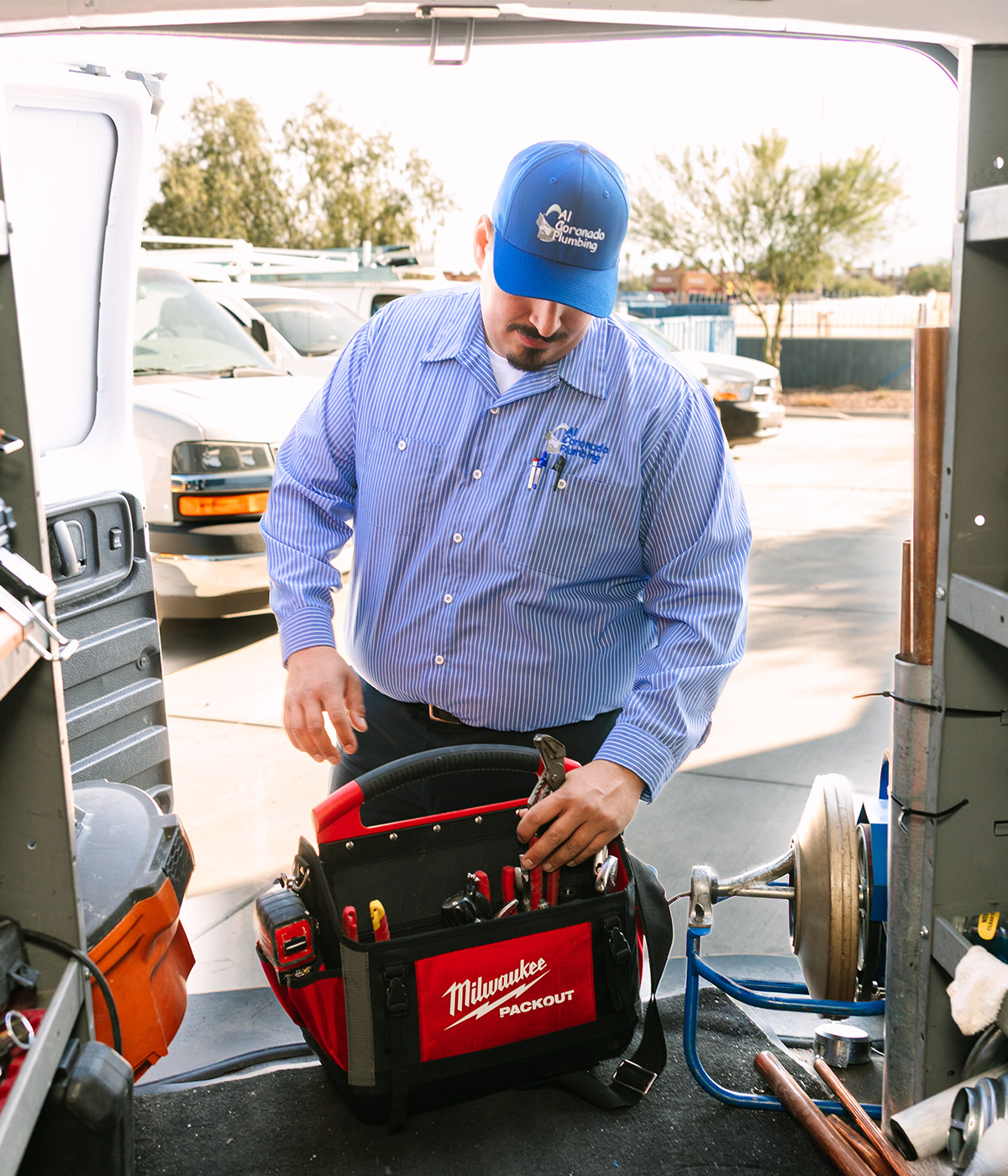 A plumber organizing tools in a Milwaukee tool bag.