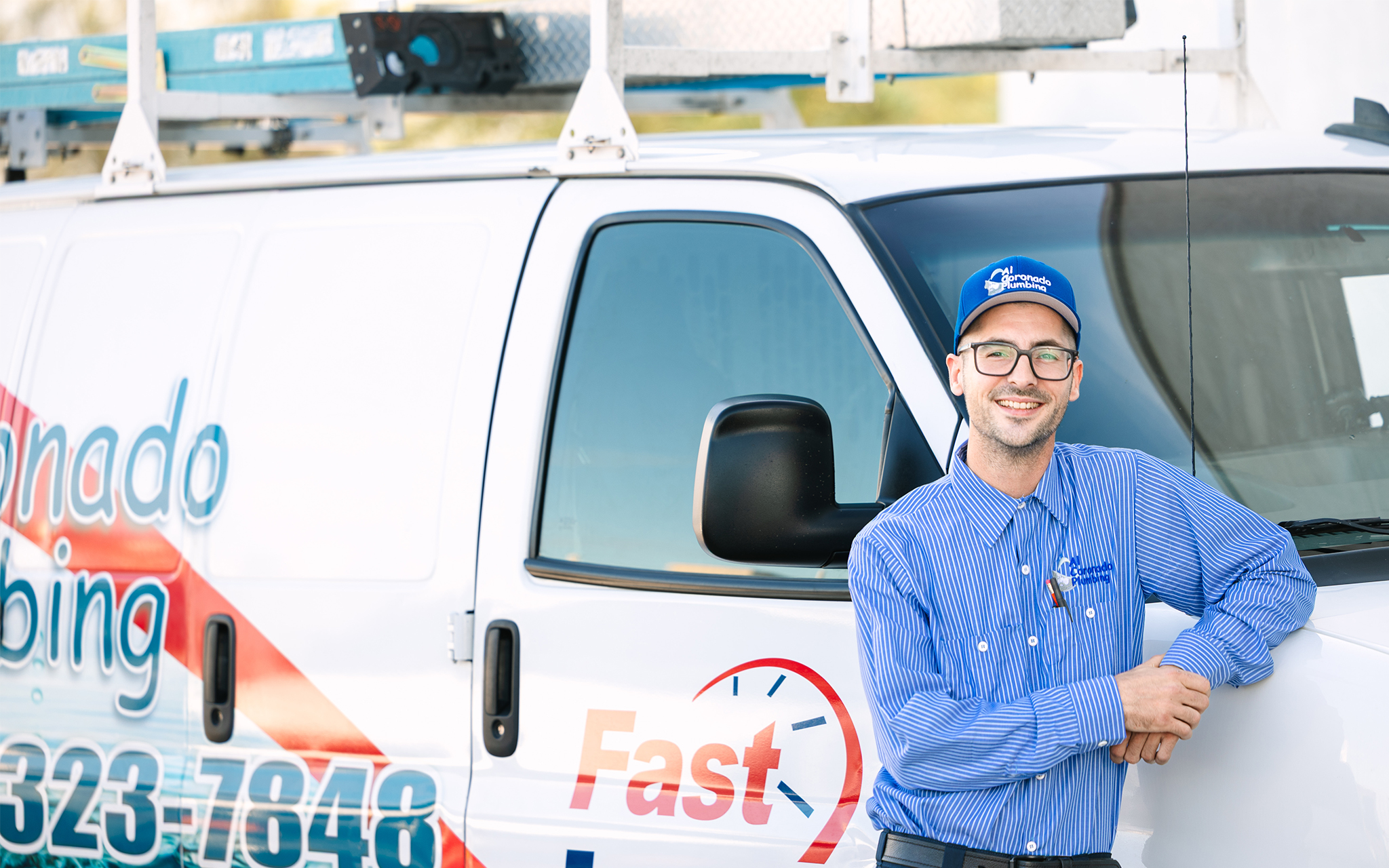 A plumbing service expert posing next to a service van